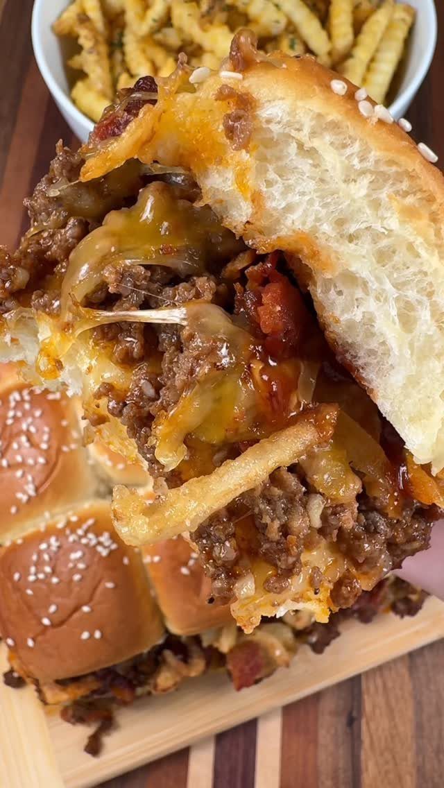 Cheesy beef sliders on sesame buns served with a side of seasoned fries.