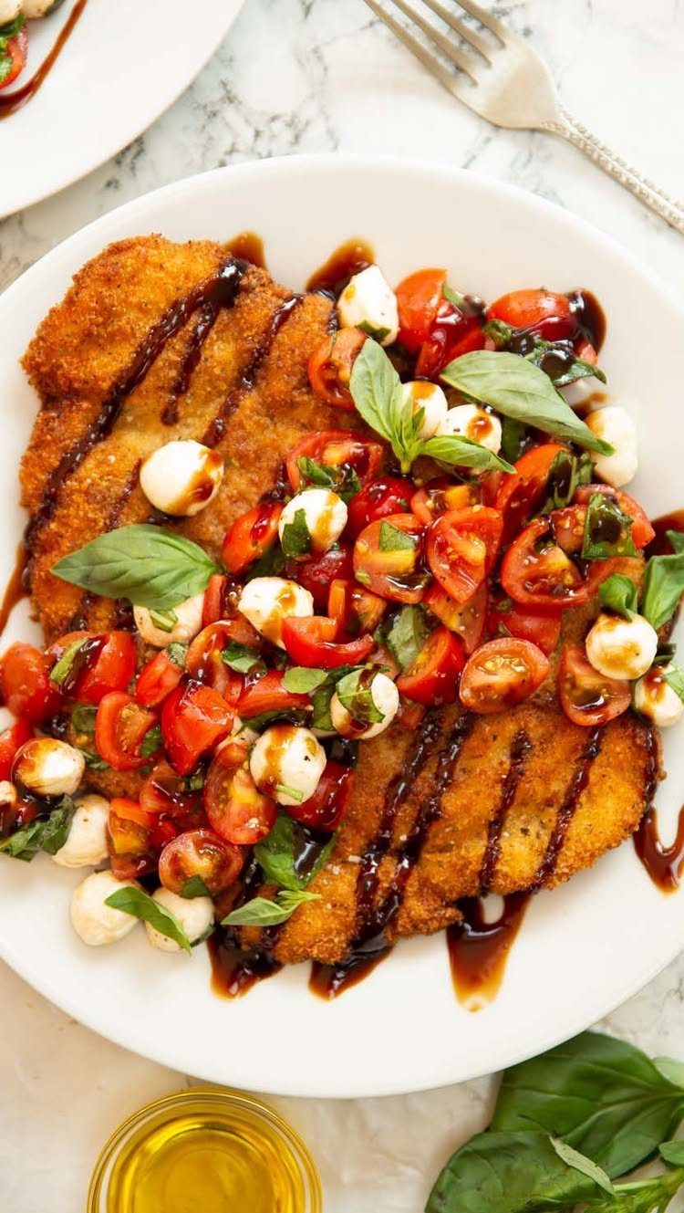 Breaded chicken breasts topped with mozzarella, cherry tomatoes, basil, and balsamic glaze.