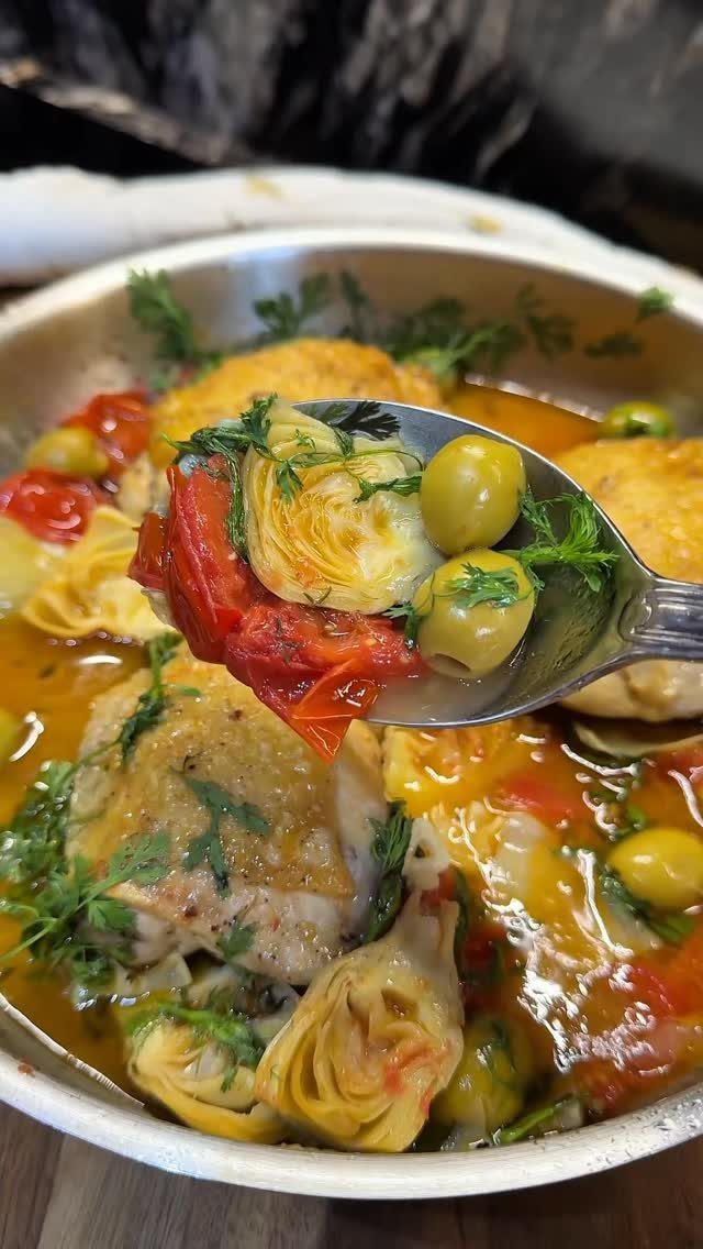 Chicken thighs in a pan with olives, artichokes, and red peppers in sauce.