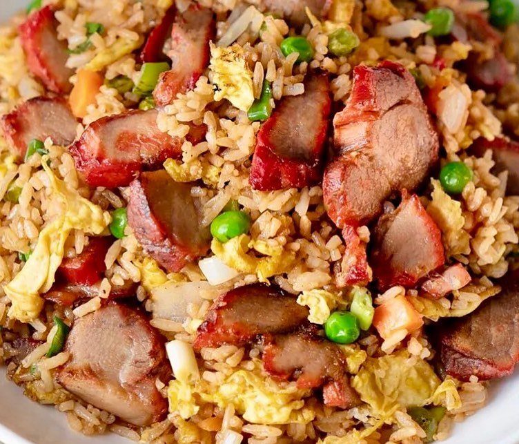 Fried rice with glazed pork chunks, green peas, and scrambled eggs on a plate.