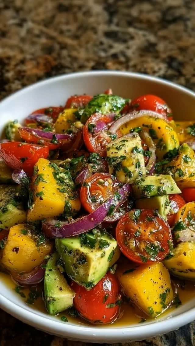Colorful fruit and vegetable salad with mango, avocado, and cherry tomatoes in a bowl.