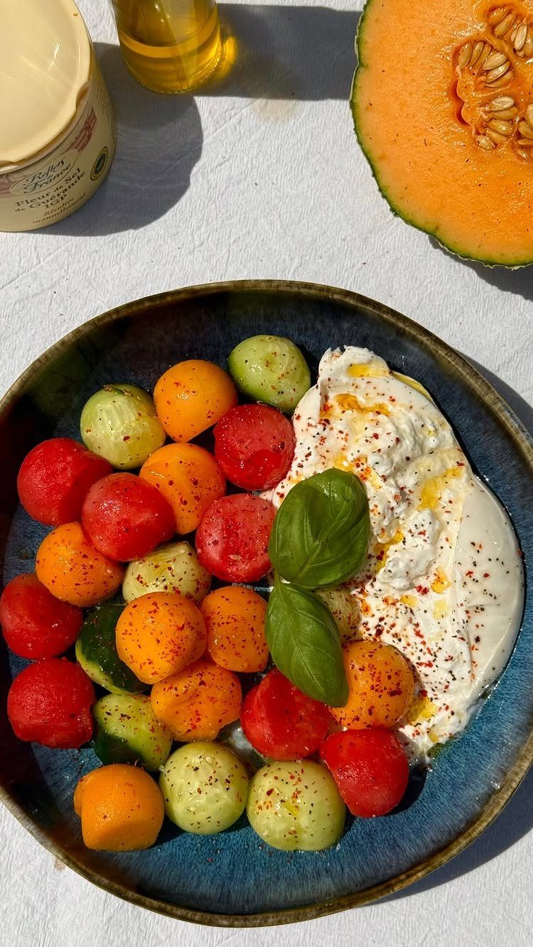 Melon salad with red, orange, and green fruit scoops and creamy cheese.