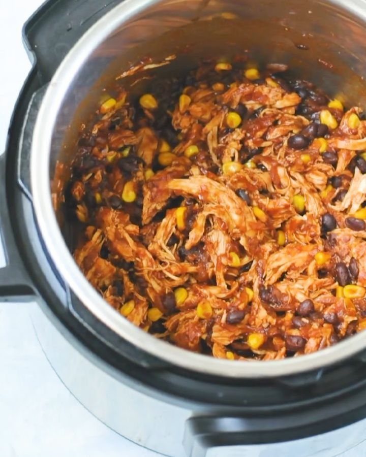 Shredded BBQ chicken with black beans and corn in a slow cooker pot.
