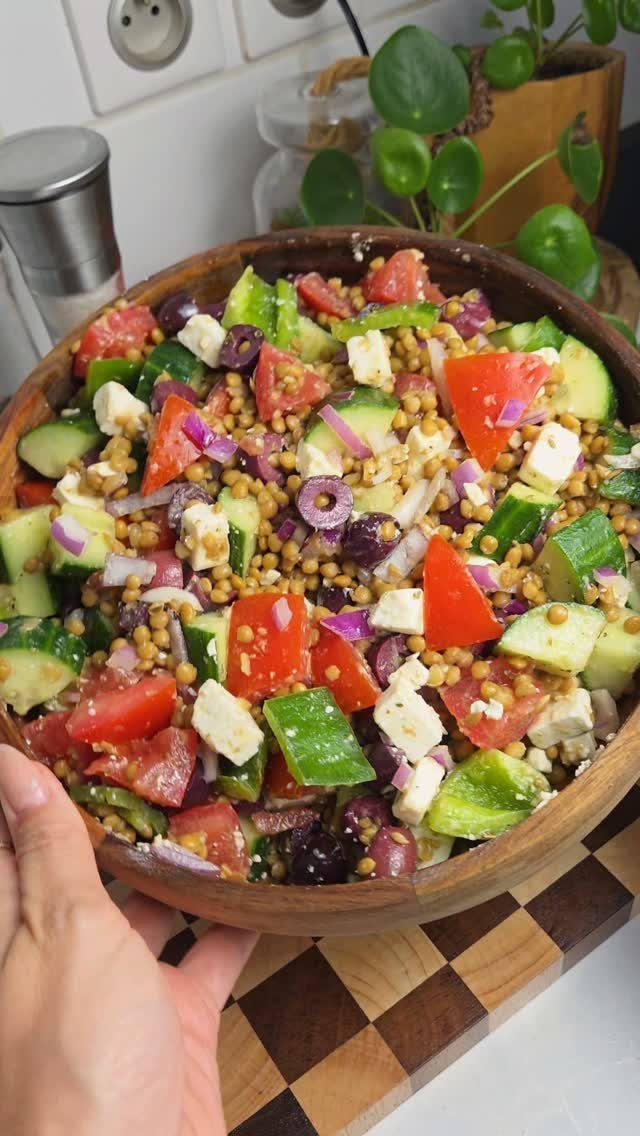 Lentil salad with cucumber, tomato, and feta cheese in a wooden bowl