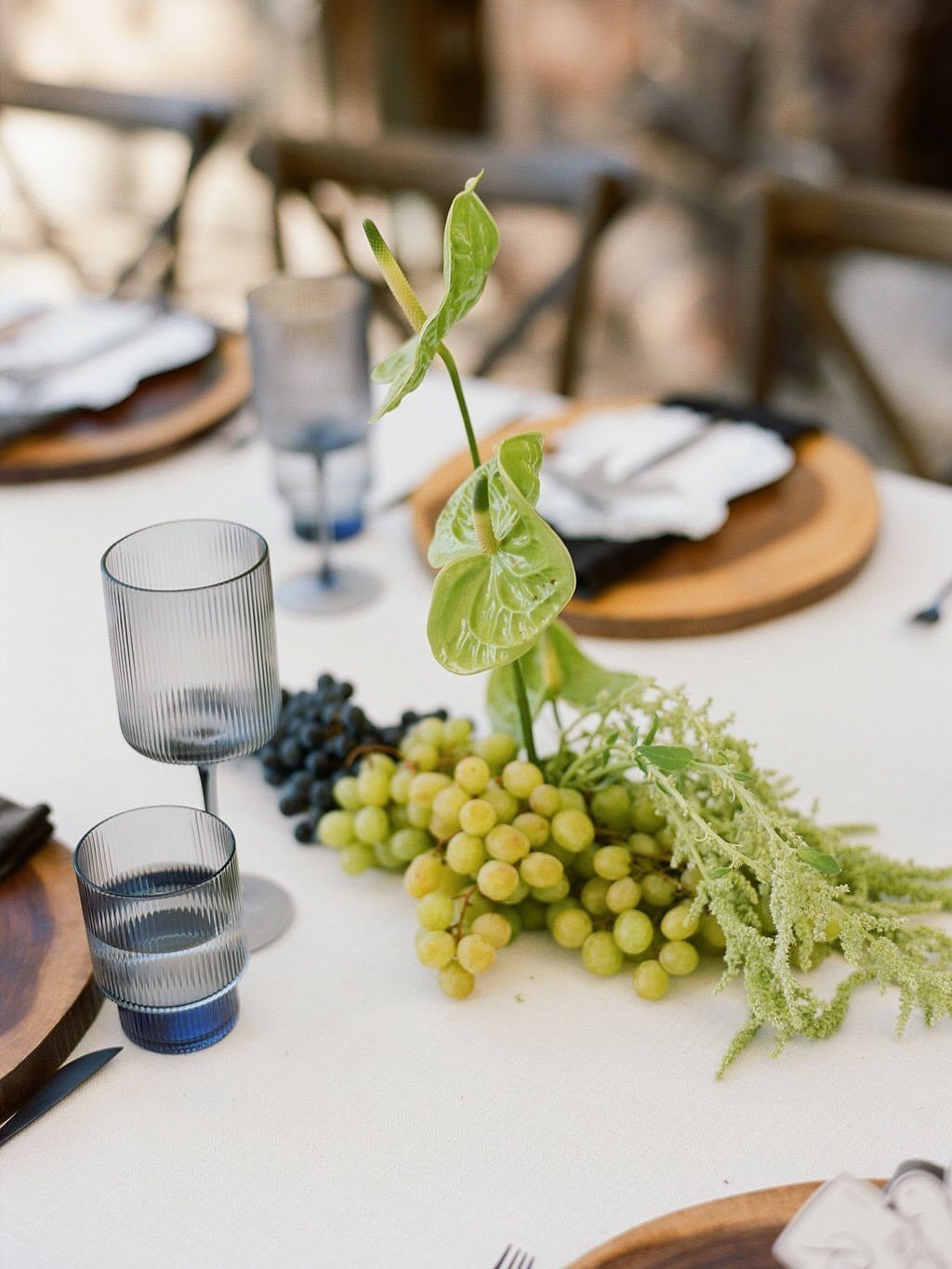 Grapes and green foliage arranged as a centerpiece on a white dining table.
