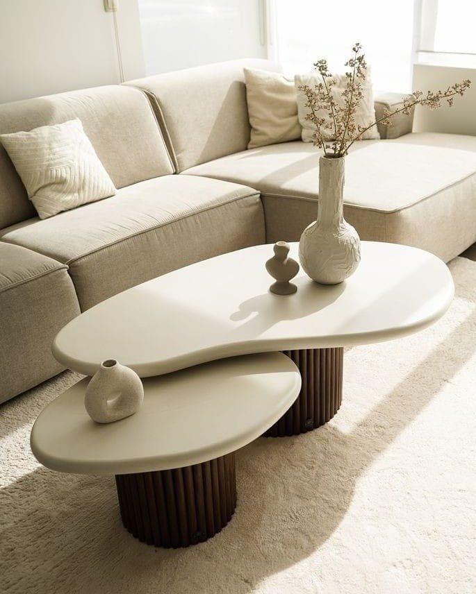 White organic coffee table with a textured vase and dried branches in a living room