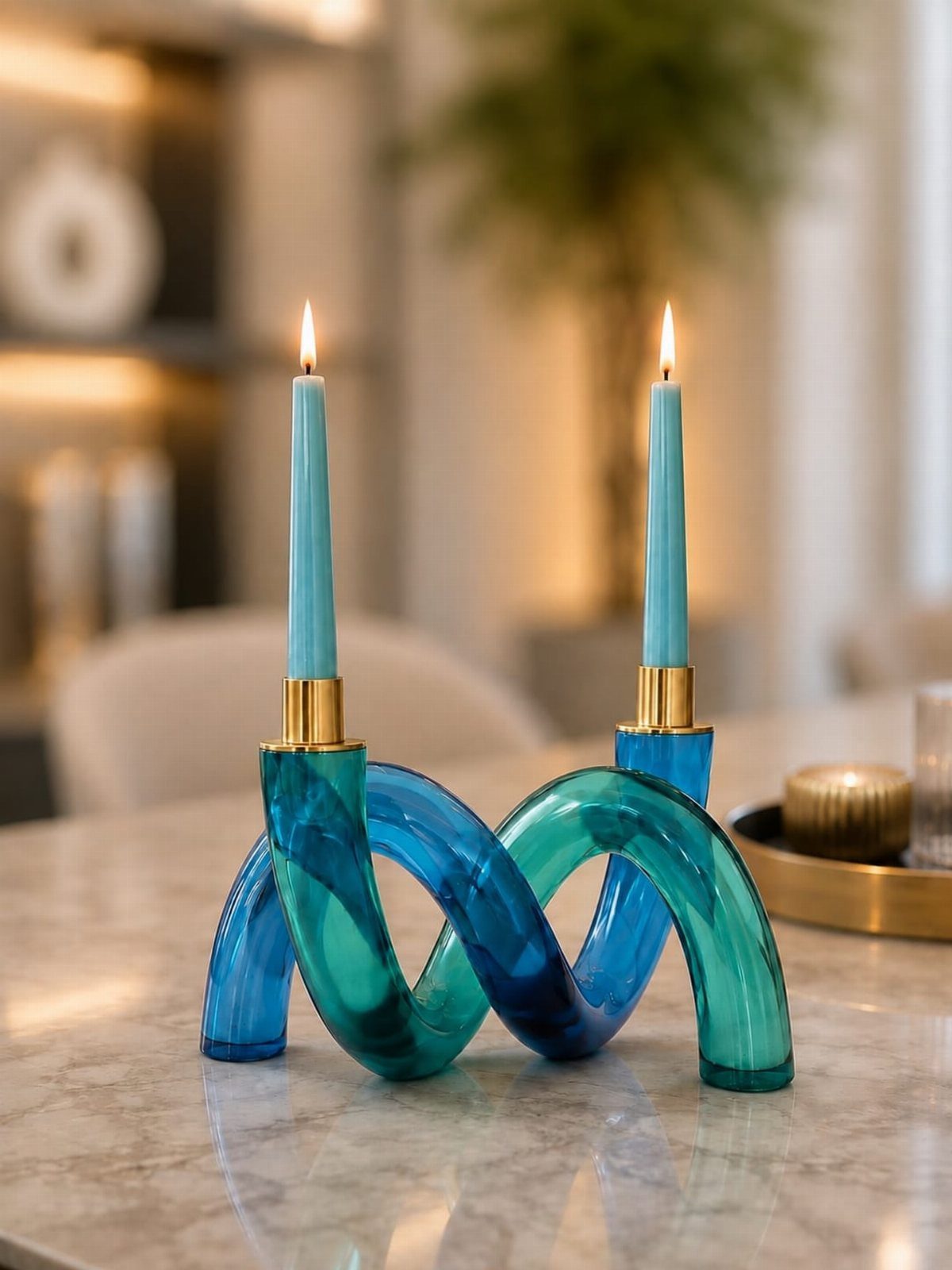 Blue twisted glass sculptural candle holder with two lit light-blue taper candles.
