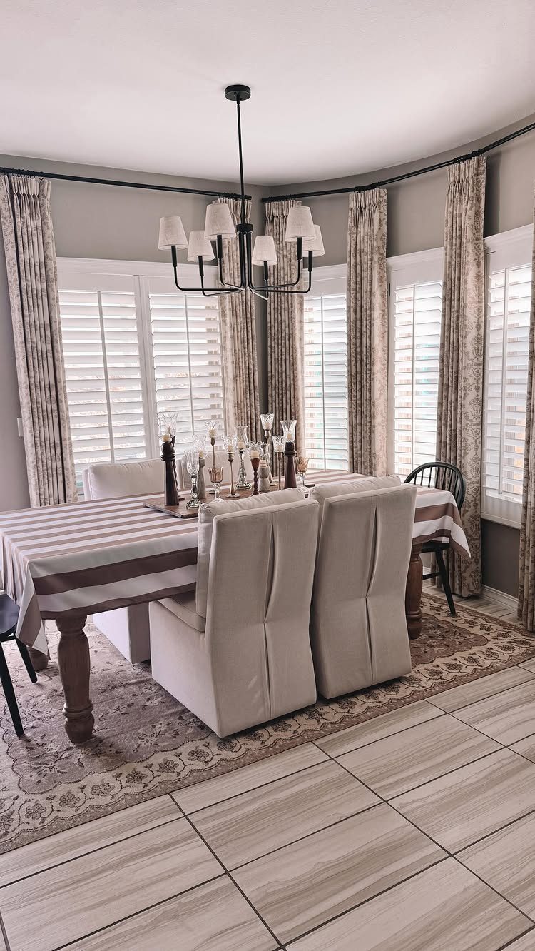 Dining table with a striped runner and a centerpiece of vintage vases and candles.