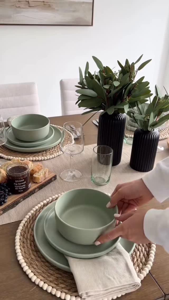 Light green bowl and plate on a beaded placemat with greenery centerpieces.
