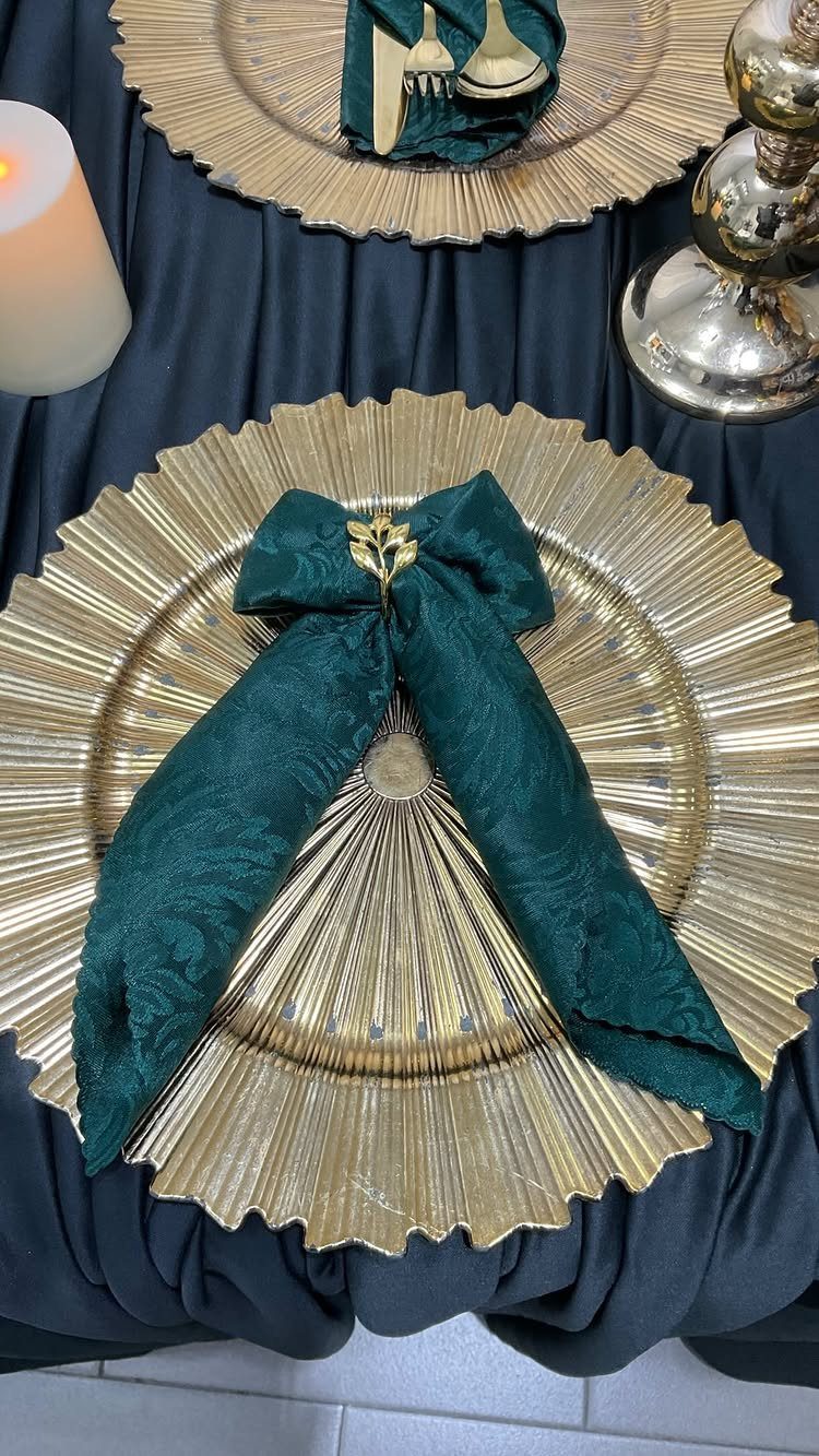 Dark green fabric napkin with gold ring placed on a gold charger plate.