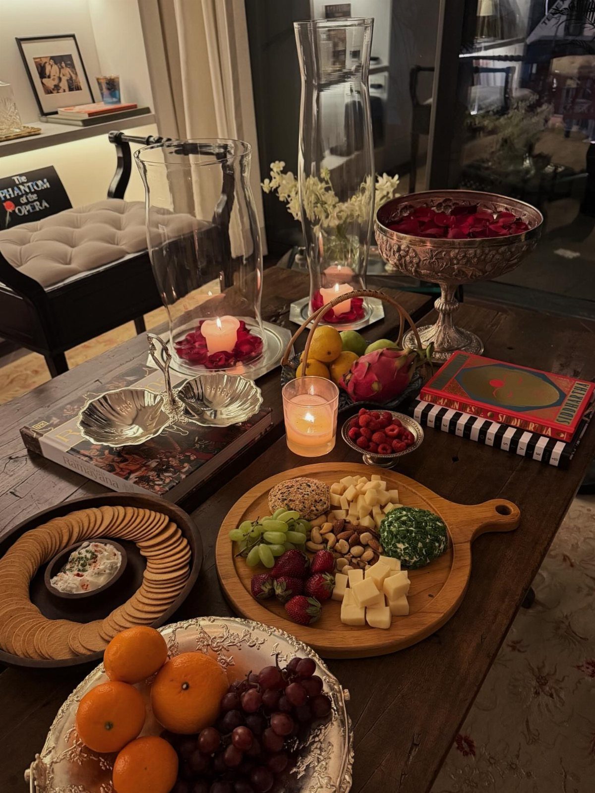 Charcuterie board and fruit platters arranged on a wooden table with candles.