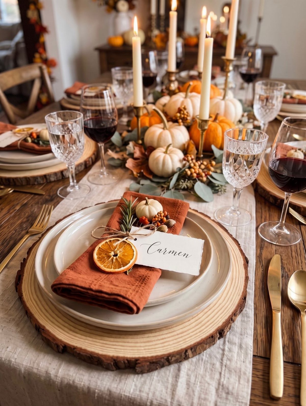Table setting with a handwritten place card, rust napkins, and pumpkin centerpieces.