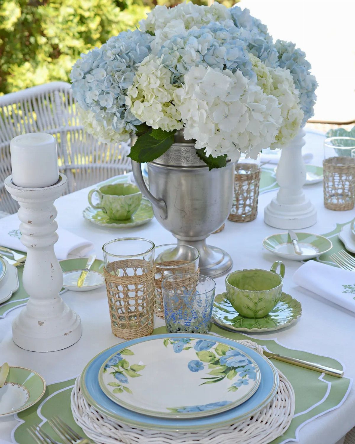 Blue and white hydrangea centerpiece in a silver vase on a tea table.