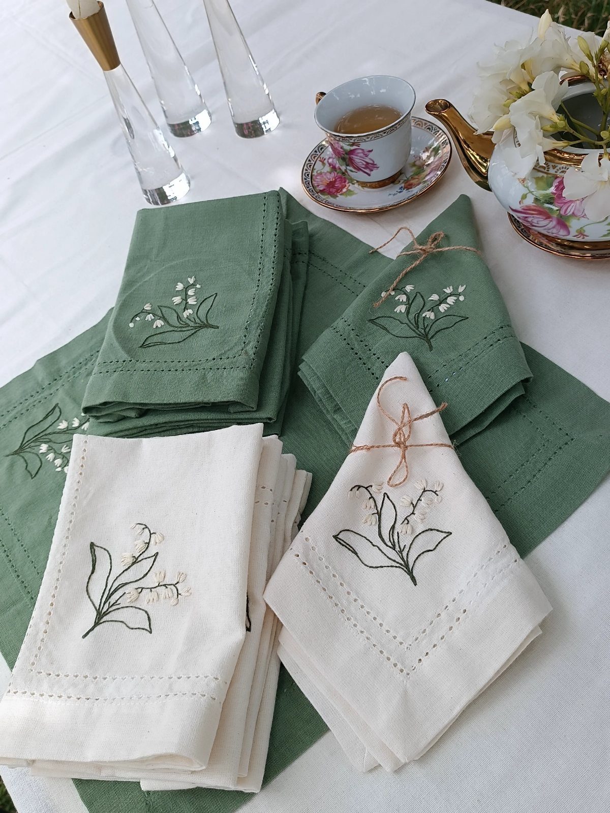 Embroidered sage green and cream linen napkins on a white tea party table