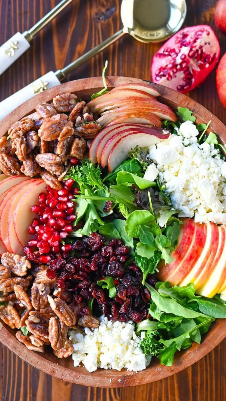 Cranberry pomegranate salad with apples, pecans, and feta in a wooden bowl.