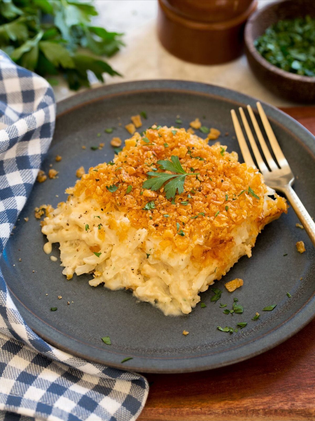Creamy corn casserole slice with crispy golden topping on a dark grey plate.