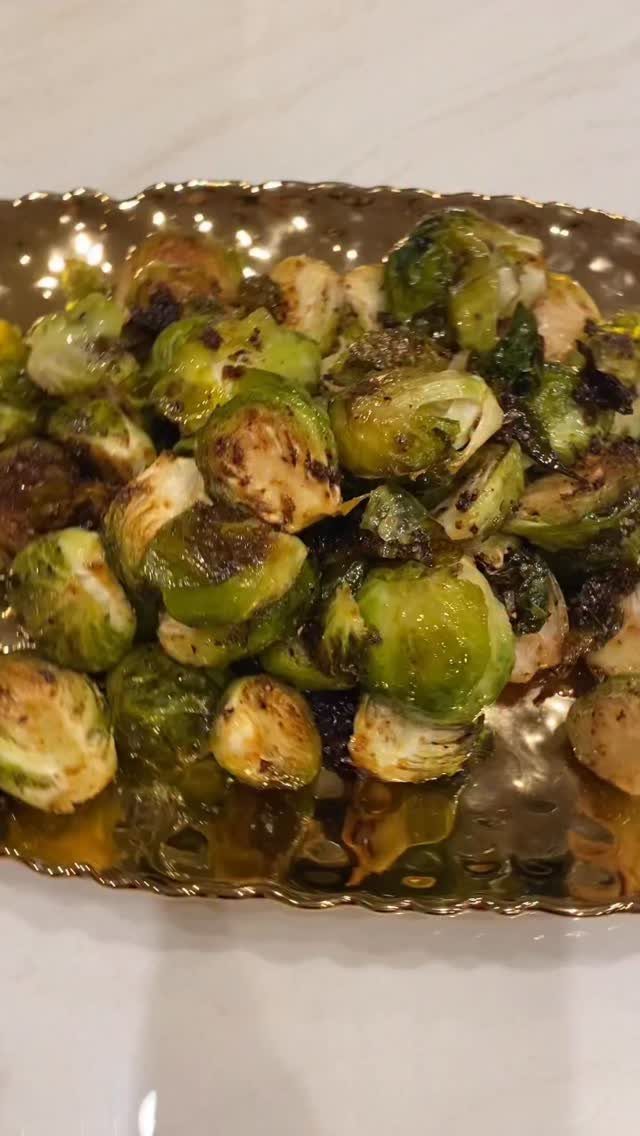 Roasted Brussels sprouts with charred edges served on a gold scalloped platter.