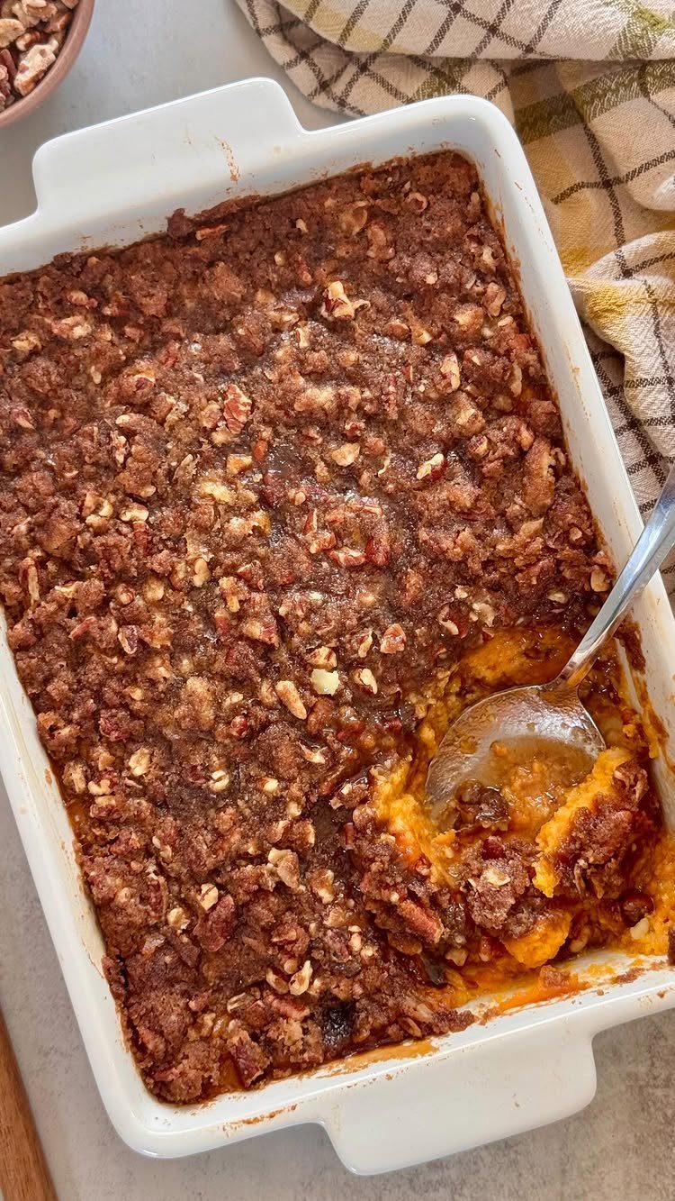 Sweet potato casserole with pecan crumble topping in a white baking dish.