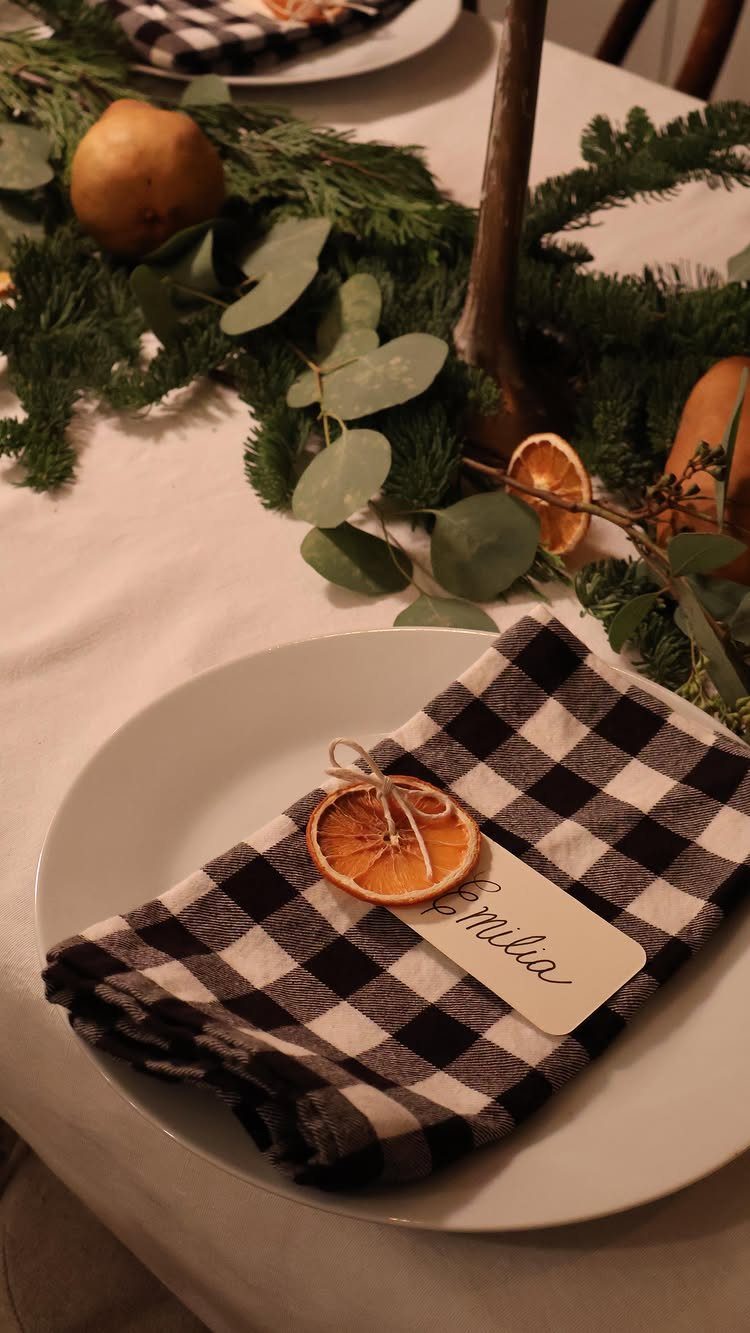 Handwritten name card for Emilia on a checkered napkin with dried orange slice.