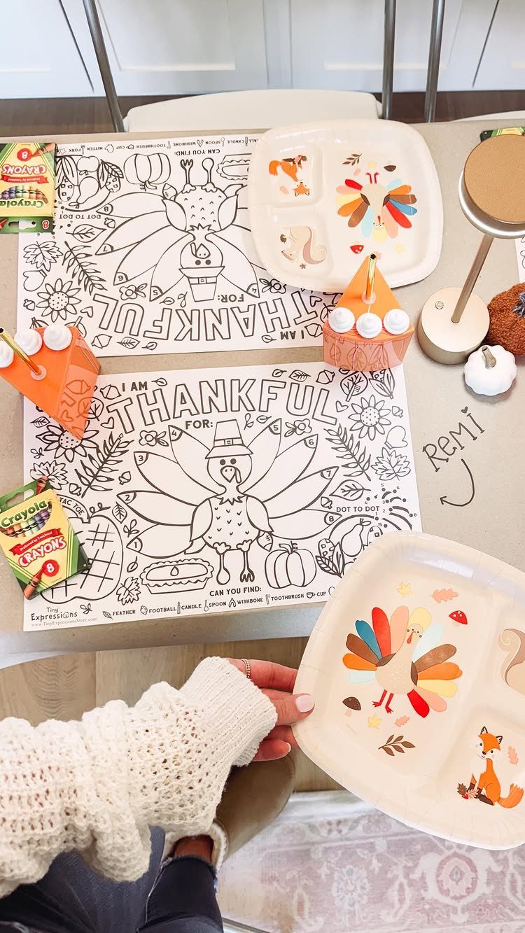 Kids' Thanksgiving table setup with turkey coloring placemats, divided plates, and crayons.