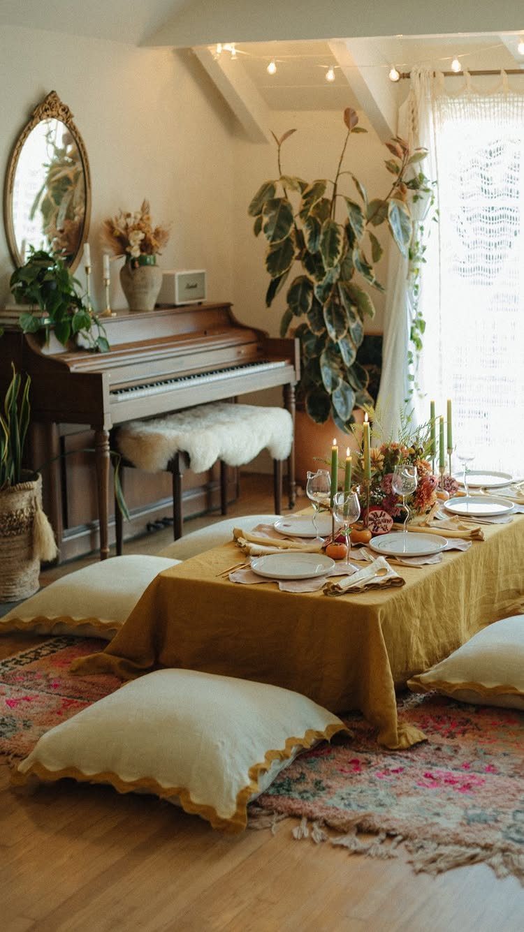 Low dining table with mustard yellow cloth, floor cushions, and organic floral centerpiece.