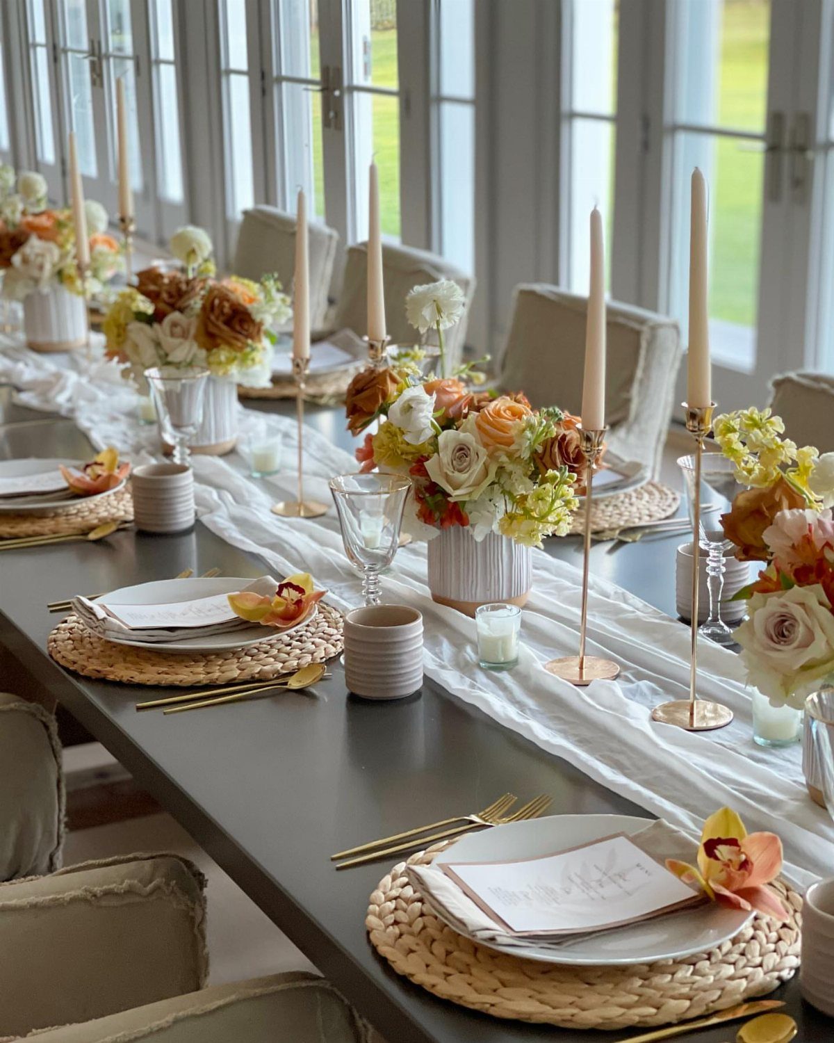 Elegant Thanksgiving table setting with neutral colors, white linens, and autumn floral centerpieces.