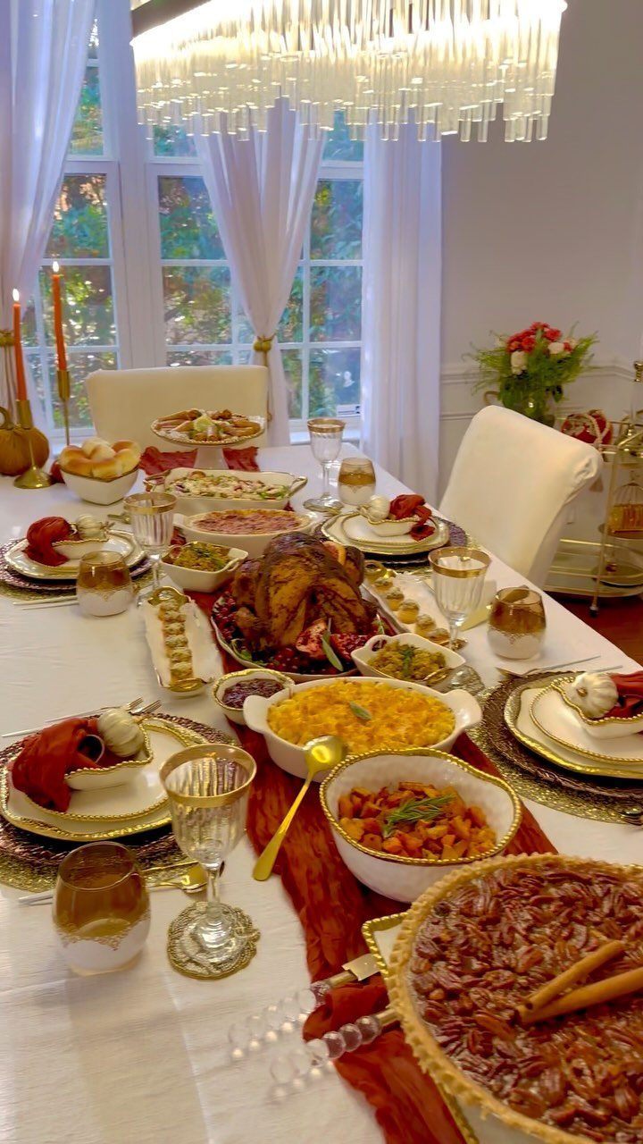 Thanksgiving dinner table with white tablecloth, roasted turkey, and various seasonal side dishes.