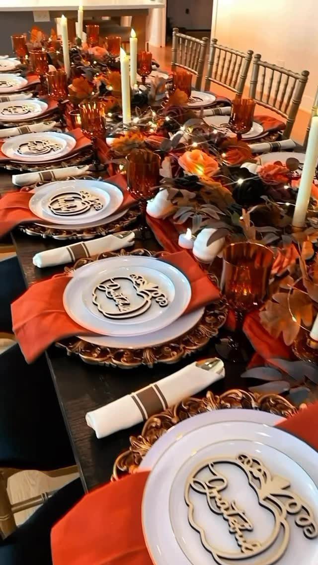 Elegant Thanksgiving table with orange napkins, gold chargers, and amber glassware.