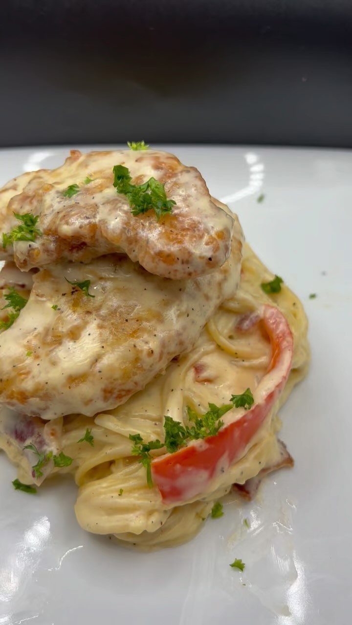 Creamy chicken carbonara pasta topped with chicken breast and red bell pepper.