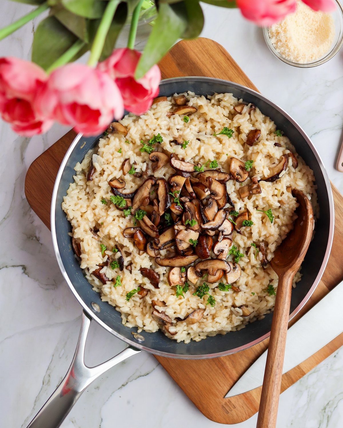 Mushroom risotto in a pan topped with sautéed mushrooms and fresh parsley.