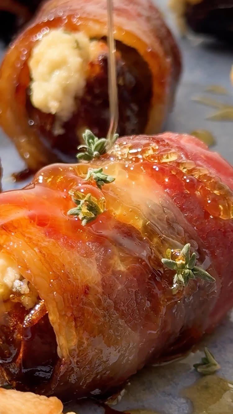 Bacon-wrapped dates stuffed with cheese, glazed with honey and garnished with fresh thyme.