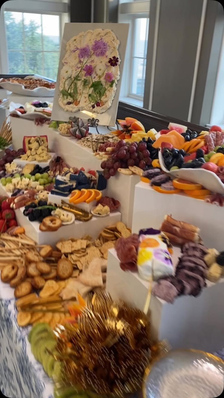 Charcuterie grazing table with tiered displays of meats, cheeses, fruits, and crackers.