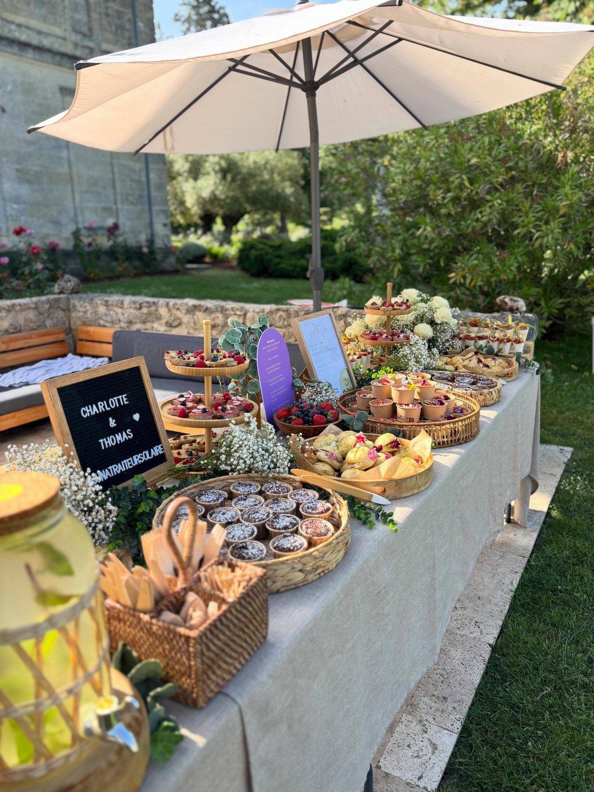 Dessert table with tarts and pastries under a white umbrella for a wedding.