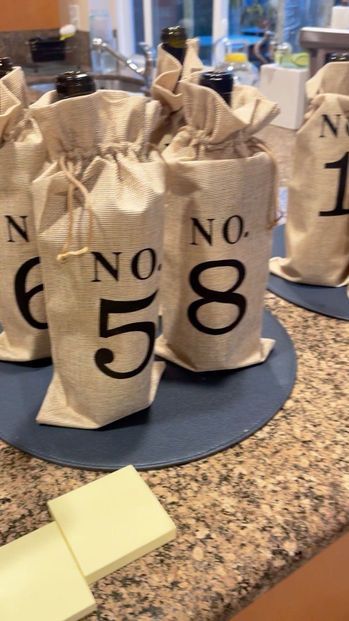 Wine bottles hidden in numbered burlap bags for a blind tasting party setup.